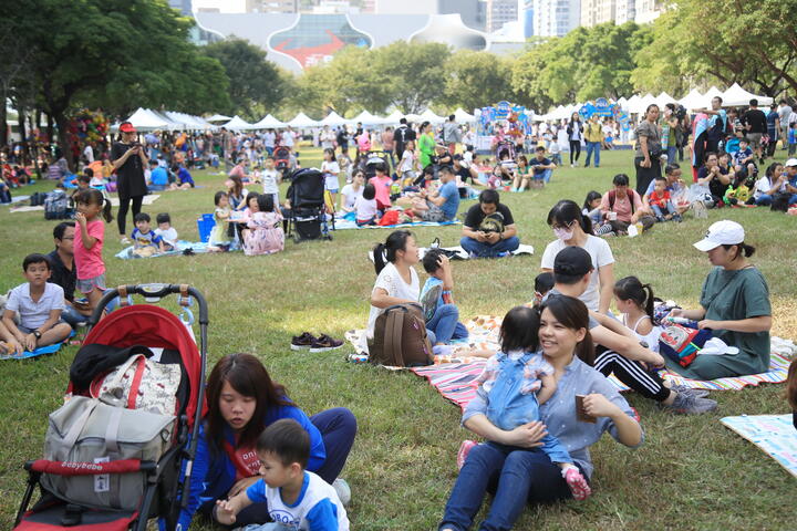 许多家长带着孩子在草地上席地而坐-享受悠闲时光