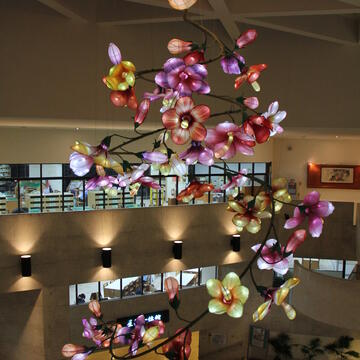 大墩文化中心馆内大厅光彩夺目-由天然染大师陈景林操刀的-槿绽-以50朵大小不一-各种色彩的花朵螺旋悬吊於大厅-采光玻璃帷幕下高达七米的装置艺术